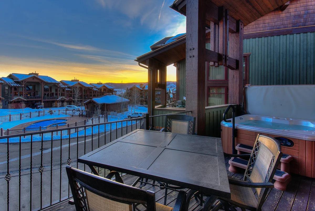 This exterior image features a private hot tub and outdoor dining table set on a deck, with a stunning sunset view in the background. The atmosphere is tranquil and inviting, perfect for unwinding after a day of adventure.