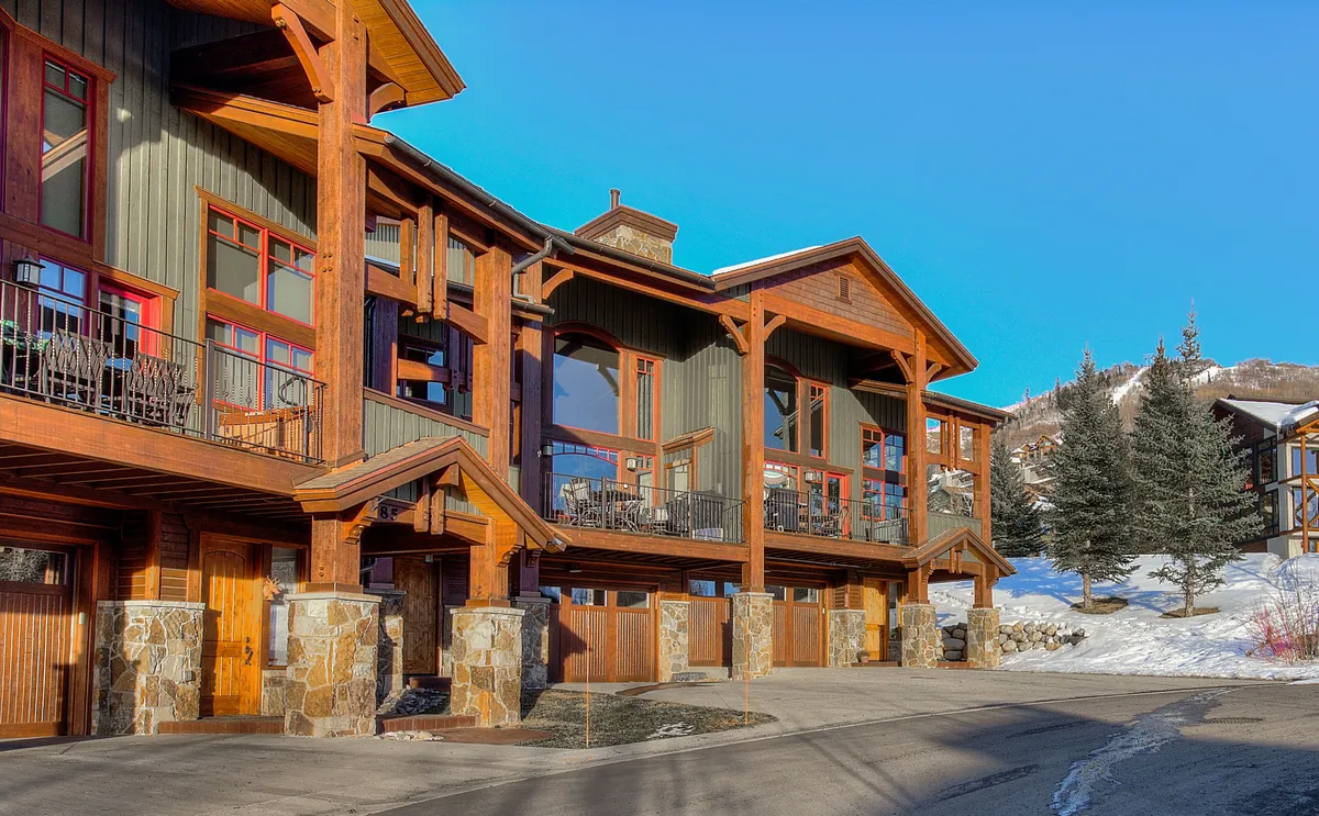 This exterior shot highlights the wooden architecture of Cimarron, with its large windows, stone pillars, and inviting balconies that overlook the surrounding mountains. The scene suggests a seamless blend of indoor comfort and outdoor adventure, with ample opportunity to take in inspiring views from multiple vantage points.